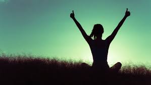 Silhouette of a seated person with arms raised against the sky